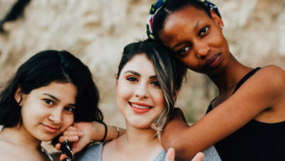 Three women standing alongside one another with natural background